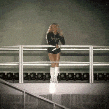 a woman stands on a balcony holding a microphone and wearing shorts that say ' aa ' on them