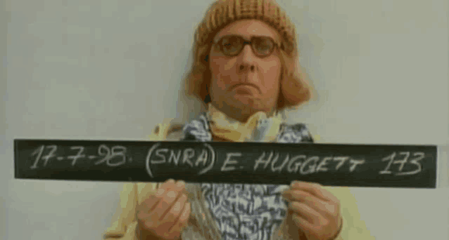a man holding a sign that says e huggett 173 on it