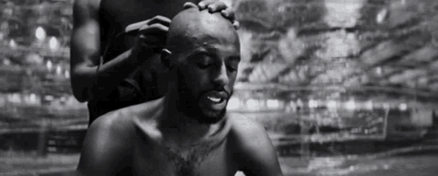 a black and white photo of a man getting his hair shaved .