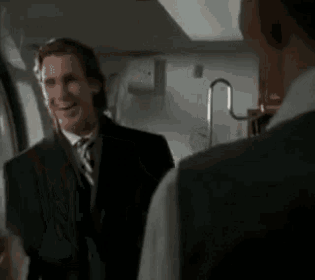 a man in a suit and tie is standing next to another man in a suit and tie on a bus .