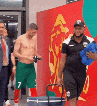 a shirtless man with the number 7 on his shorts is walking