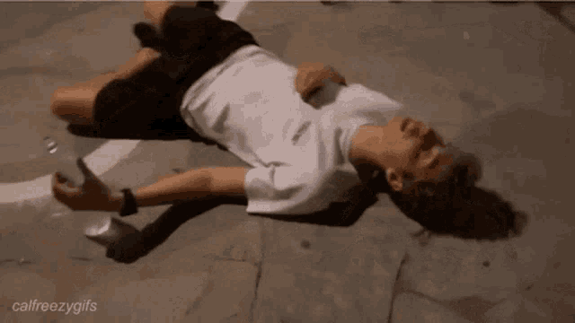 a man is laying on the ground with a bottle of water .