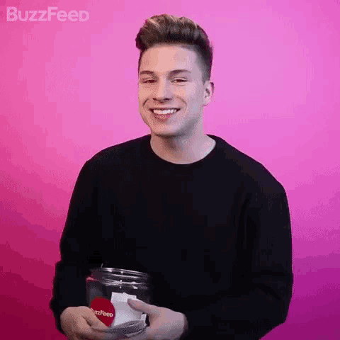 a young man in a black sweater is holding a jar with a heart in it .