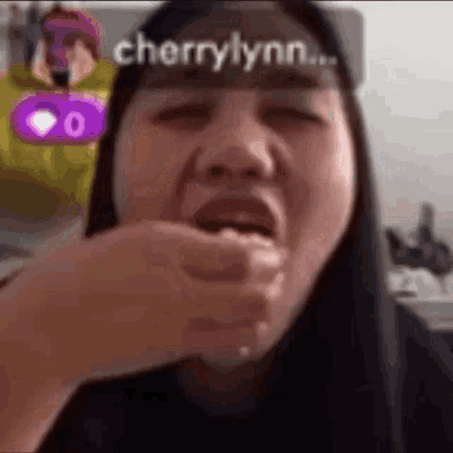 a woman is making a funny face with her mouth open and the name cherrylynn on her head .