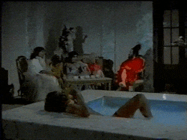 a woman is laying in a bathtub in front of a group of women