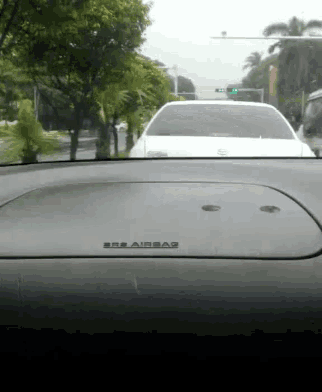 a white car is driving down a street with an airbag on the dash