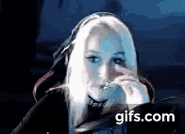 a woman with blonde hair and headphones is sitting in front of a computer monitor .
