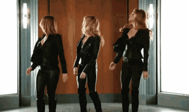 three women are standing next to each other in a room dancing .