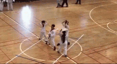 a group of people are practicing martial arts on a wooden floor .