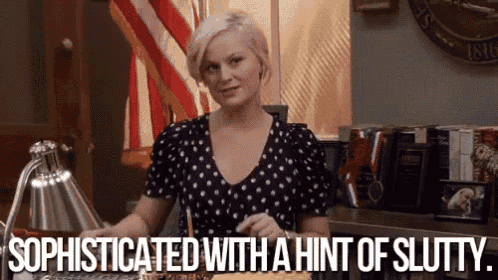 a woman in a polka dot shirt is standing in front of a desk and says sophisticated with a hint of slutty