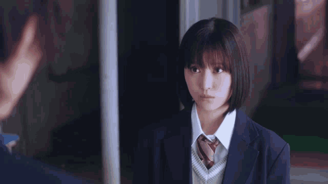 a girl in a school uniform is looking at another girl