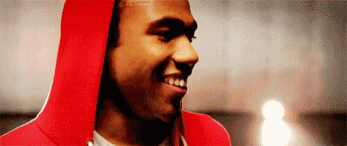 a man wearing a red hoodie is smiling and looking at the camera .
