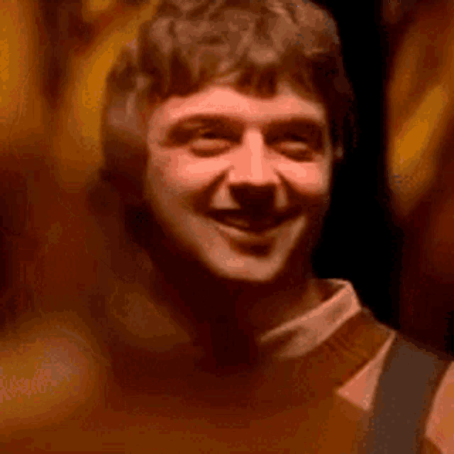 a close up of a man 's face with a blurry background and a smile on his face .