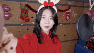 a woman wearing a reindeer headband is taking a selfie in front of a microphone