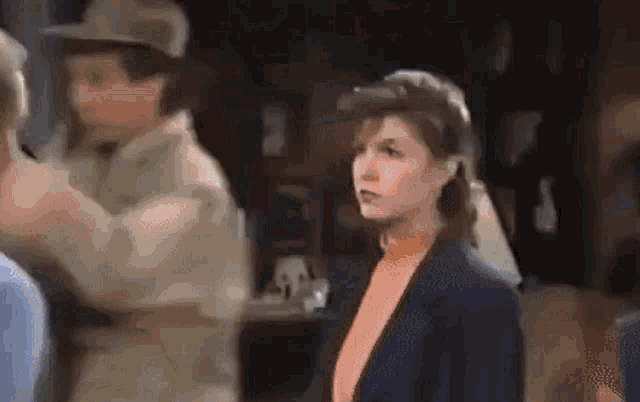 a woman in an orange sweater is standing in front of a man in a tan hat .