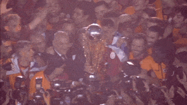 a man is holding a trophy surrounded by other people