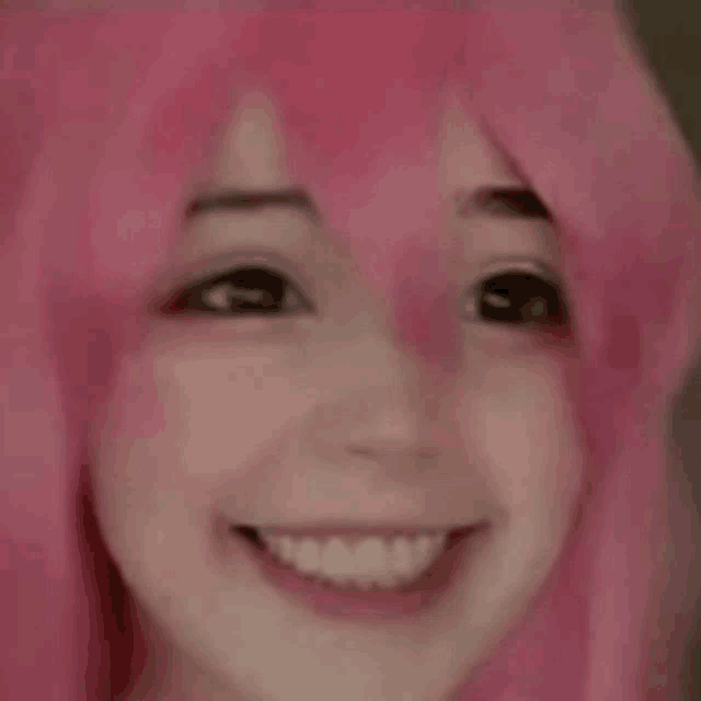 a close up of a person wearing a pink wig smiling .