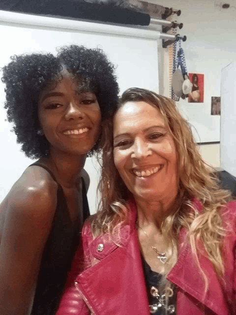 two women are posing for a picture and one of them is wearing a pink leather jacket
