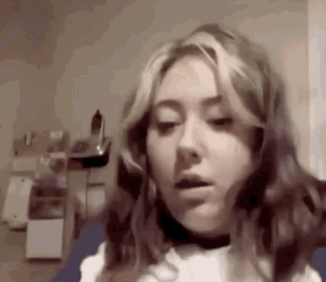 a close up of a woman 's face with a telephone in the background