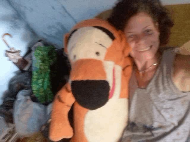 a woman is holding a stuffed tigger bear and smiling