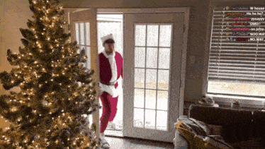 a man dressed as santa claus is standing next to a christmas tree