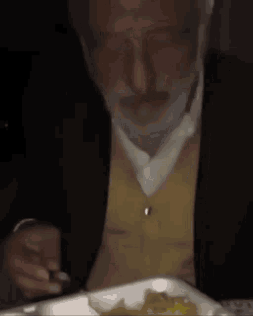 a man with a beard is sitting at a table with a plate of food and the word ou yes is on the bottom