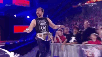 a man in a black tank top with the word ambrose on it walks on a stage