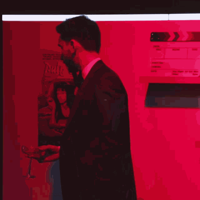 a man in a suit is holding a glass of wine in front of a pulp fiction poster