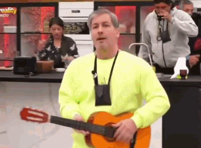 a man in a neon green sweater is holding a guitar .
