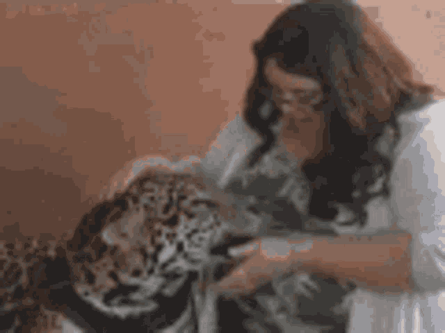 a woman is petting a small tiger in a room .