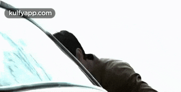 a man is cleaning the windshield of a car with a wiper .