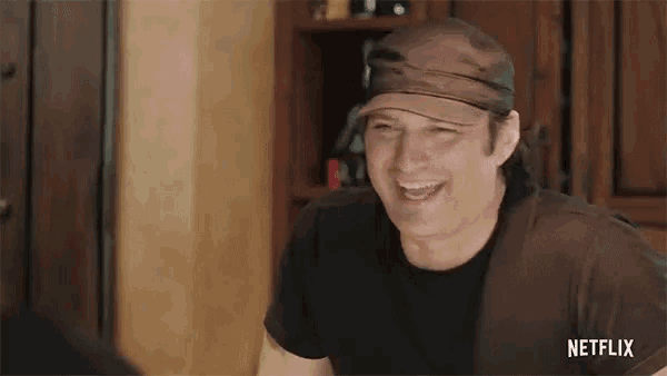 a man wearing a hat and a black shirt is laughing in a netflix advertisement