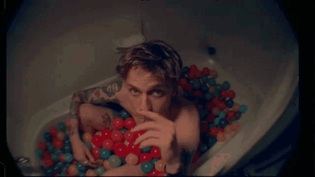 a man is laying in a bathtub filled with colorful balls