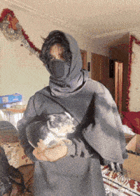 a person wearing a mask is holding a small dog in their arms