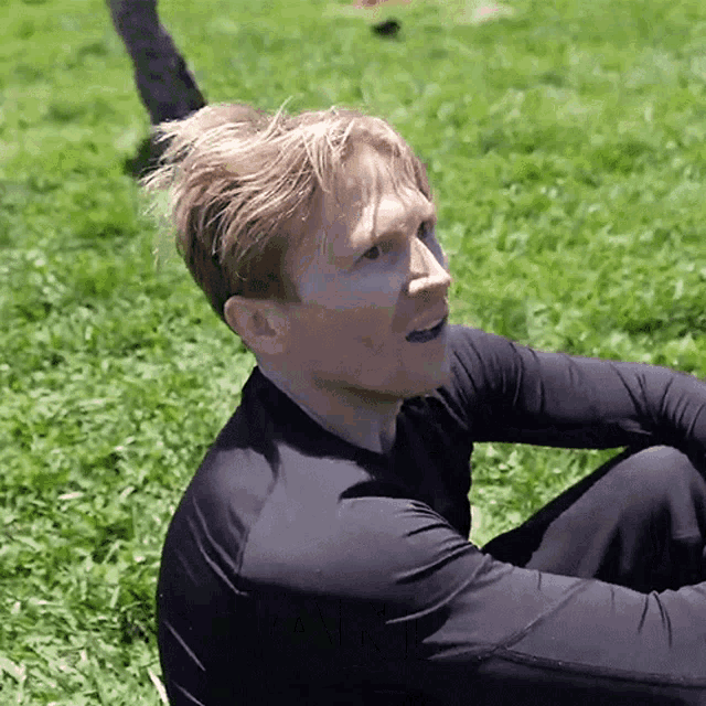 a man wearing a black shirt is sitting in the grass