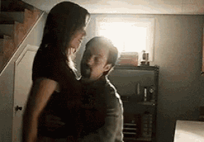 a man is holding a woman in his arms in a room in front of a window .