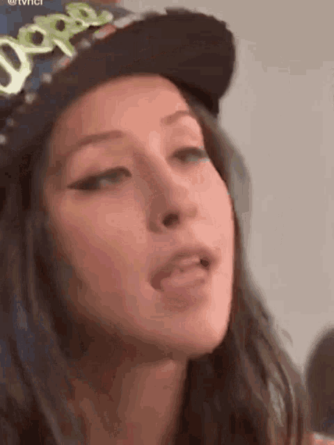 a close up of a woman wearing a hat making a funny face .