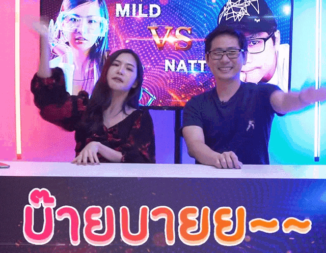 a man and a woman are standing in front of a screen that says mild vs natt