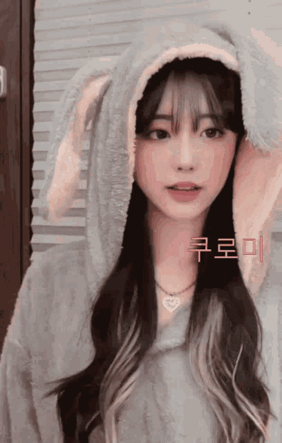 a girl wearing bunny ears and a heart necklace has korean writing on her face