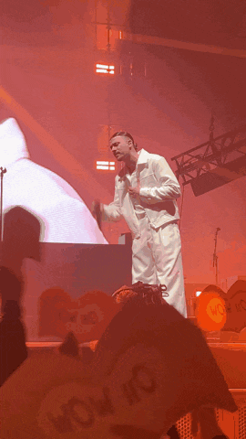 a man in a white suit sings into a microphone on a stage