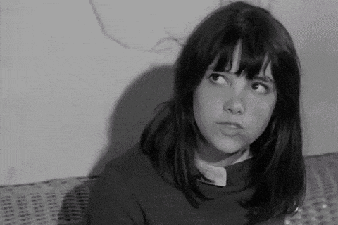 a young girl is sitting on a wicker couch and looking up .