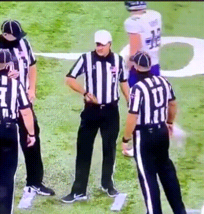 a group of referees standing on a field with one wearing a jersey that says ' u ' on it