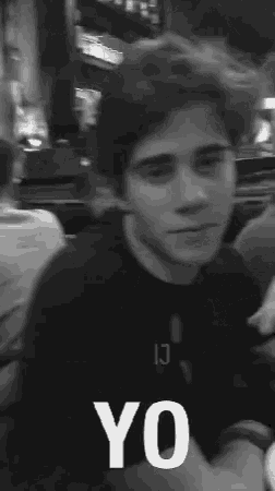 a black and white photo of a young man sitting at a table with yo written in white