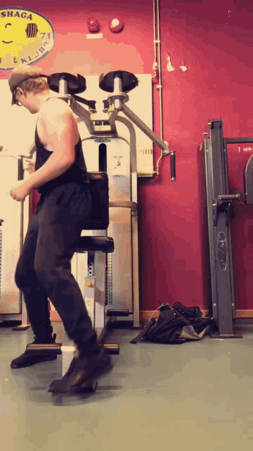 a man is doing exercises in a gym with a sign on the wall that says shaga