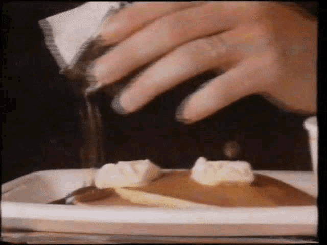 a close up of a person pouring syrup on a pancake