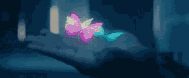 a person is holding a glowing butterfly in their hand .