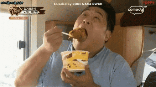 a man is eating food from a cup with a spoon while a comedy tv logo is visible
