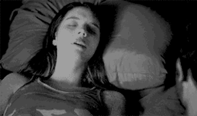 a woman is laying on a bed with her eyes closed and a pillow .