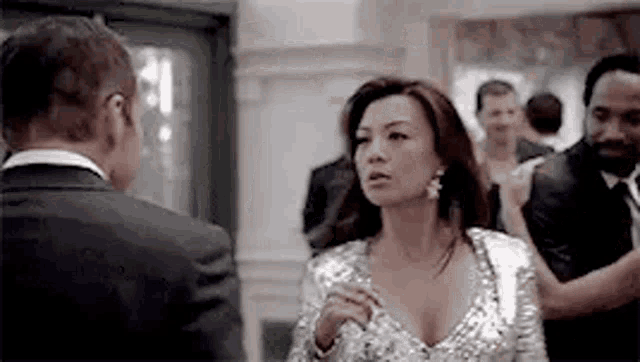 a woman in a silver dress is standing next to a man in a suit and tie .