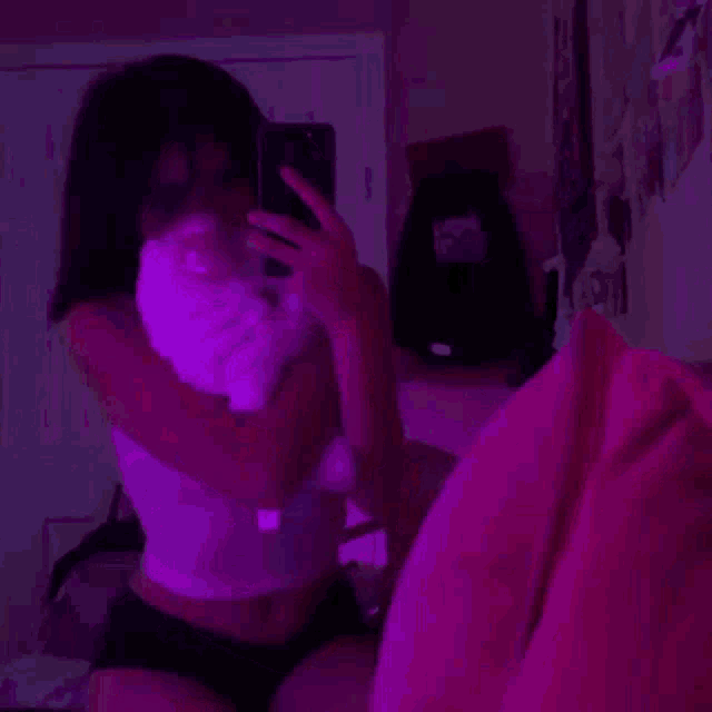 a girl is taking a selfie with a cat in her hand .